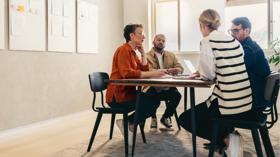 Réunion entre 4 collègues dans un bureau autour d'une table avec un ordinateur