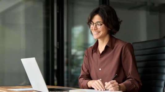 Leende kvinna vid laptop