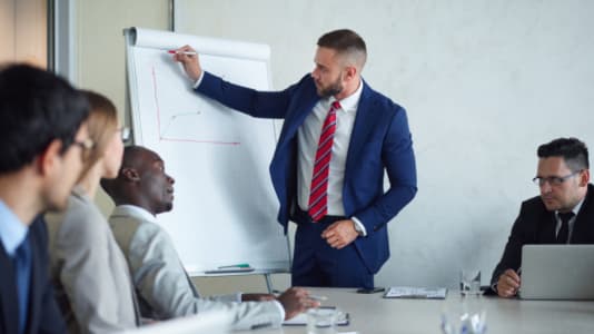 Man i mötesrum som skriver på tavla