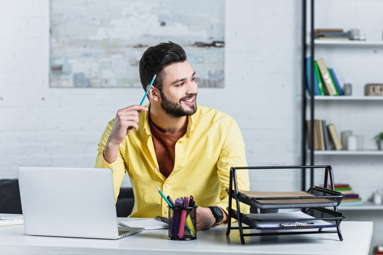 Smiling businessman holding pencil and looking away